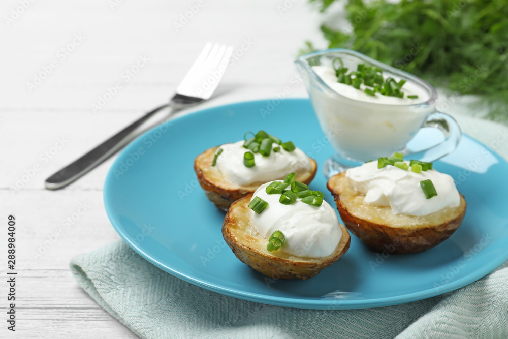 Delicious potato wedges with sour cream on white wooden table