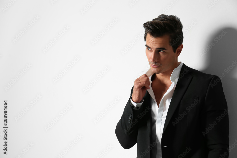 Handsome young man in elegant suit on light beige background. Space for text Handsome young man in elegant suit on light beige background. Space for text