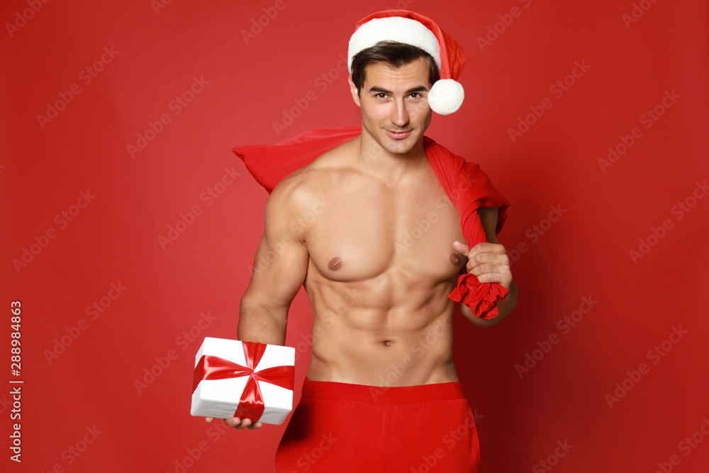 Sexy shirtless Santa Claus with gift on red background Sexy shirtless Santa Claus with gift on red background