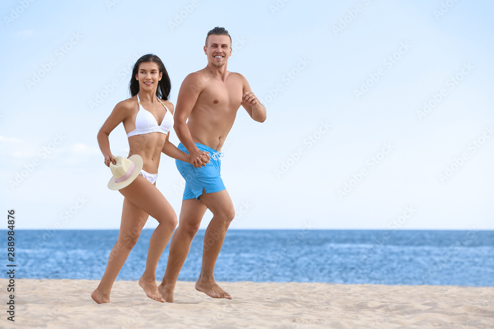 Young woman in bikini spending time with her boyfriend on beach. Lovely couple