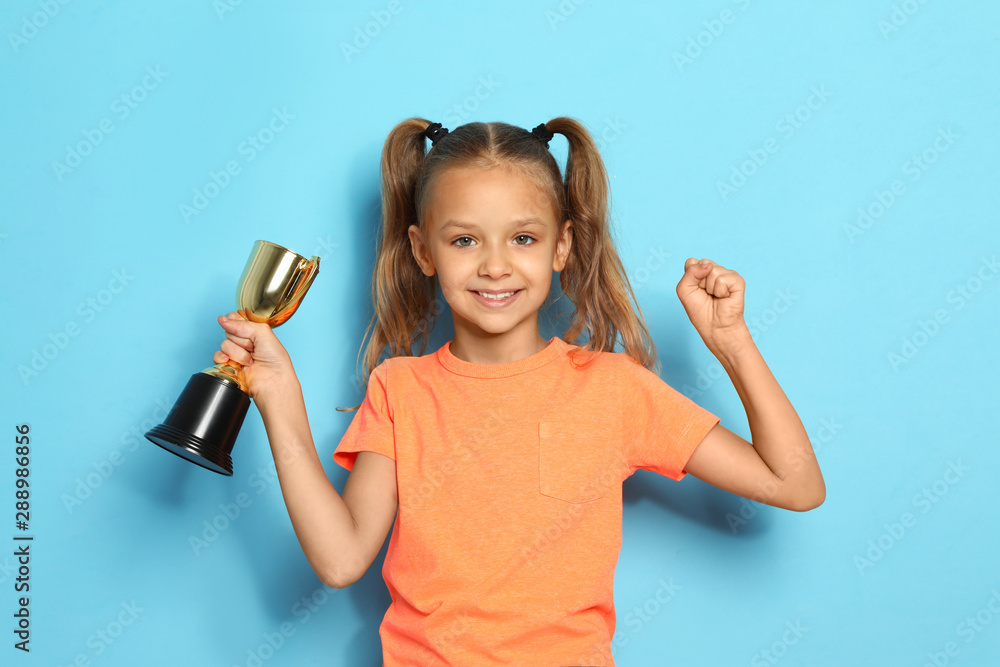 Happy girl with golden winning cup on blue background Happy girl with golden winning cup on blue background