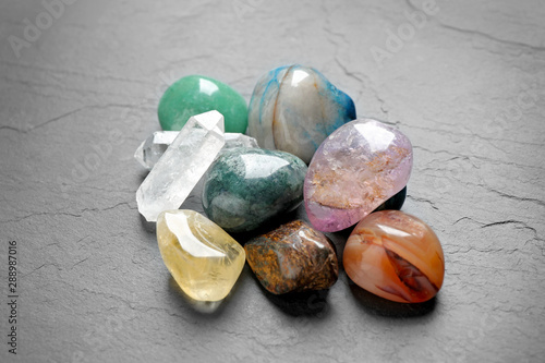 Pile of different beautiful gemstones on grey background photo