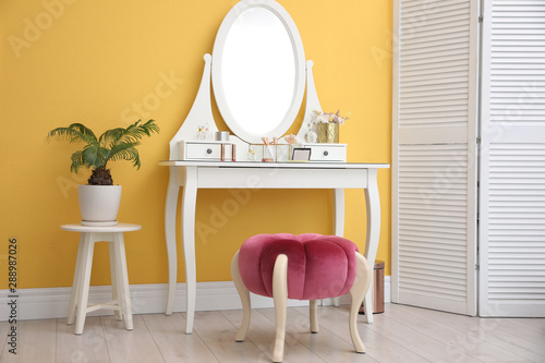 Stylish room interior with modern dressing table near yellow wall © New Africa
