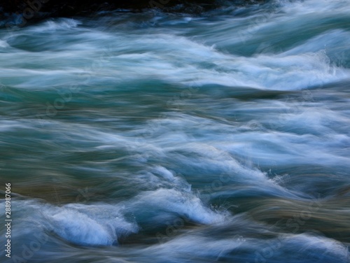 waves and ripples from a mountain stream are rendered with a slow shutter speed to give a smooth  silky feel to the photograph