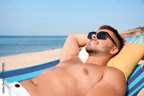 Young man relaxing in hammock on beach