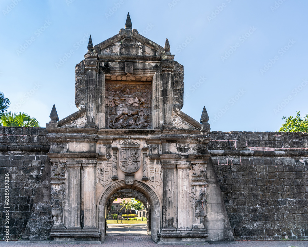 Manila, Philippines - March 5, 2019: Fort Santiago. Monumental main gate into the fortress with images of Saint James on his horse, and the coat of arms of King of Spain, all in gray stones covered in