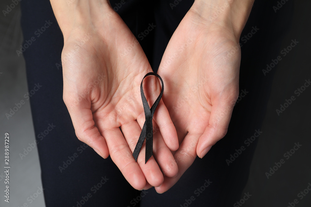 Young woman holding black ribbon, closeup. Funeral symbol Young woman holding black ribbon, closeup. Funeral symbol