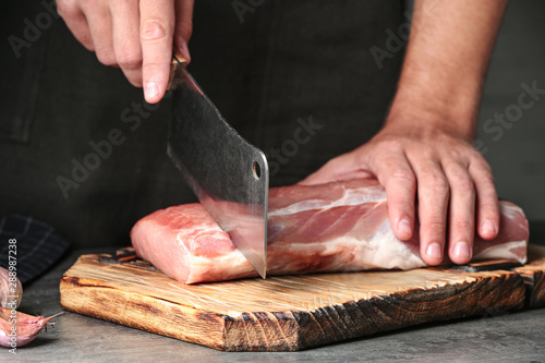 Man cutting fresh raw meat on grey table, closeup
