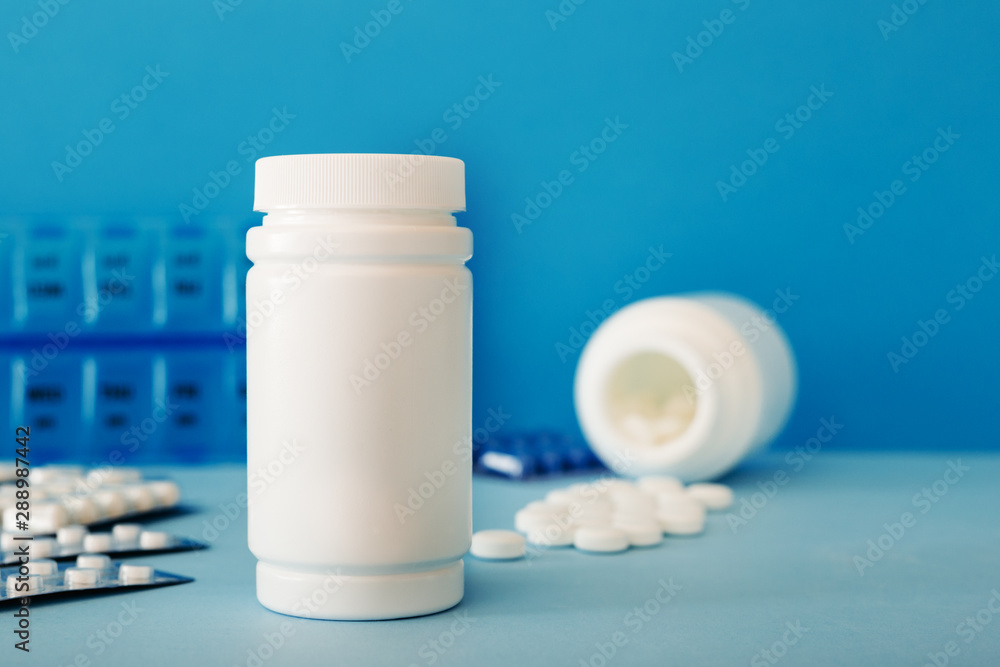 White medical pills and tablets spilling out of a bottle. Mock up bottles with copy space. White medical pills and tablets spilling out of a bottle. Mock up bottles with copy space.