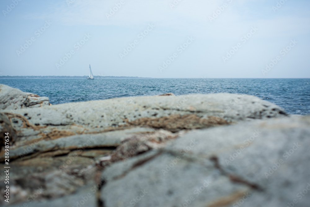 Sailboat in distance with rocks in foreground