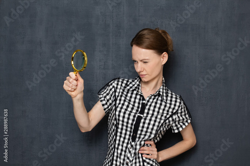 Focused girl is looking with curiosity through magnifier photo