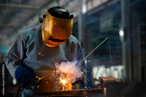 Industrial welder is welding metal part in the factory. photo