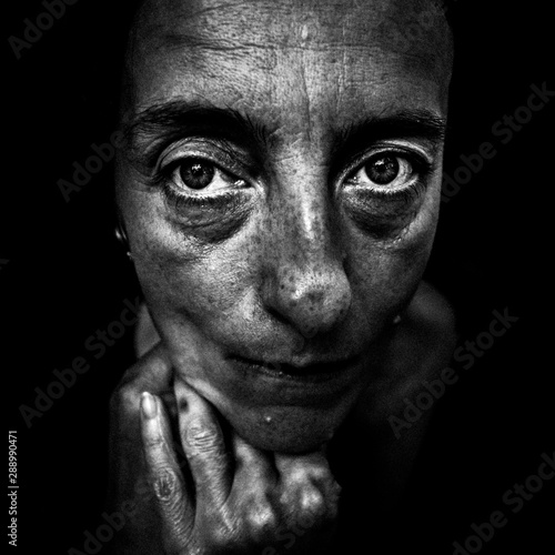 Black and white artistic portrait of a sad woman, looking straight into the camera (with added film grain)