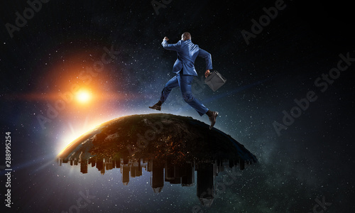 Back view of a black businessman running on the Globe with city scyscrapers on the starry space background