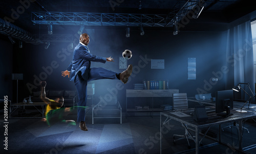 Black businessman in a suit playing footbal © Sergey Nivens