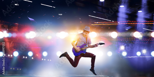 Guitar player jumping with guitar while playing