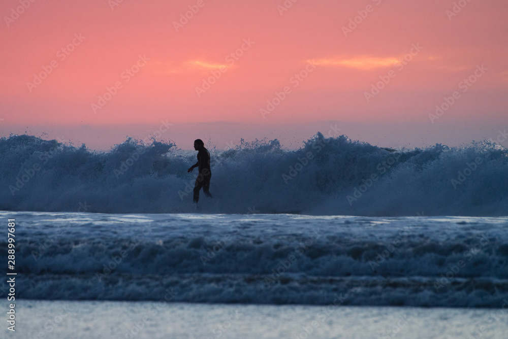 silhouette of a surfer during sunset on ocean waves in California