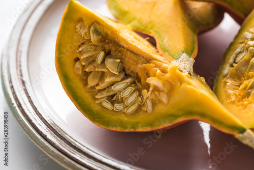 plate with fresh ripe pumpkin quarters with seeds
