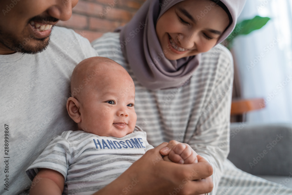 close up of asian baby boy smiling while sitting on parent's lap at home close up of asian baby boy smiling while sitting on parent's lap at home