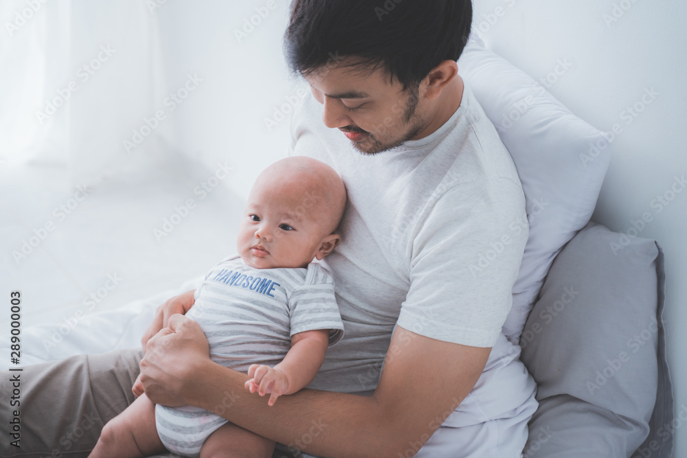 asian father with his son playing together while on the bed asian father with his son playing together while on the bed