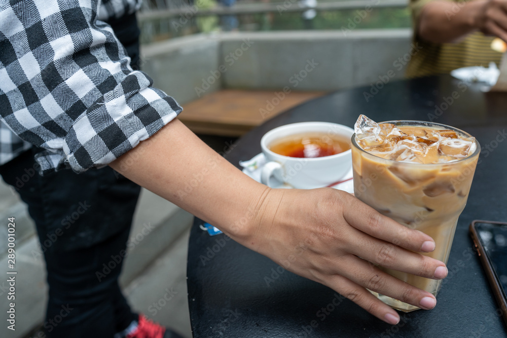 An asian or latina waitress tserving drinks of coffee and tea to customer in an outdoor cafe An asian or latina waitress tserving drinks of coffee and tea to customer in an outdoor cafe