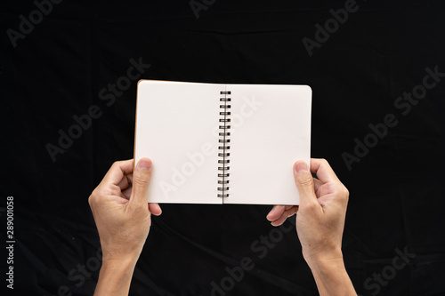 Man hand holding blank notebook on black background