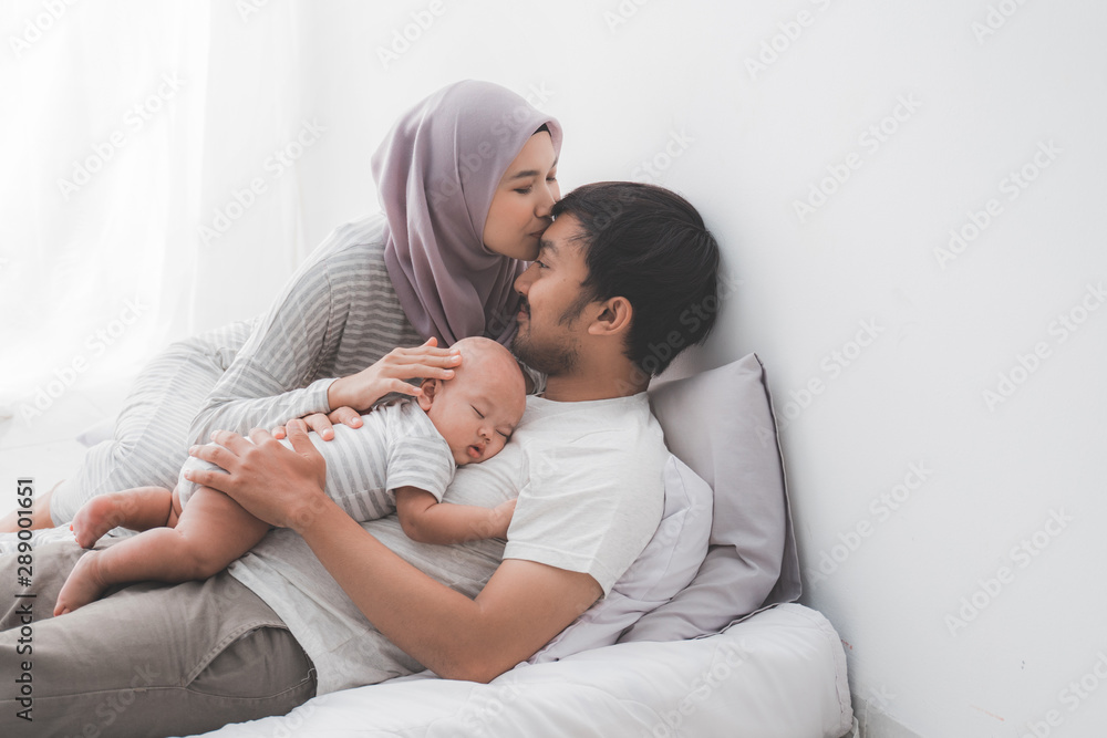 muslim parent kissing together with baby boy at home muslim parent kissing together with baby boy at home