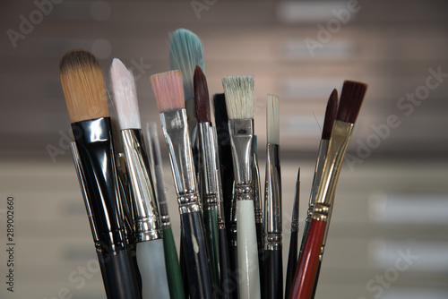 Container of artist brushes with creative lighting and file cabinet in background