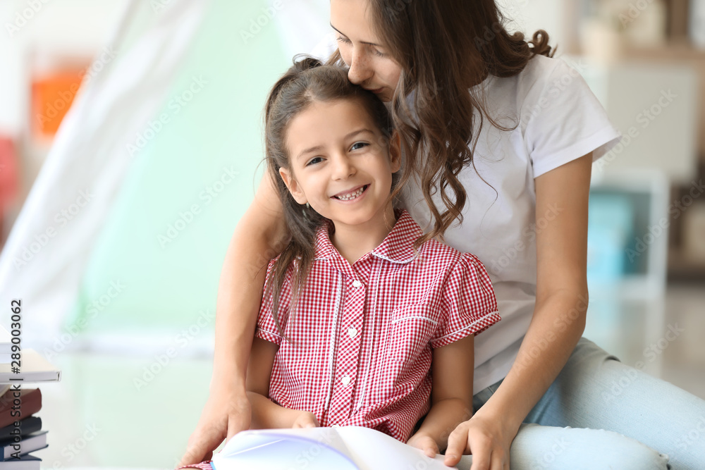 Cute little girl and her elder sister reading book at home Cute little girl and her elder sister reading book at home