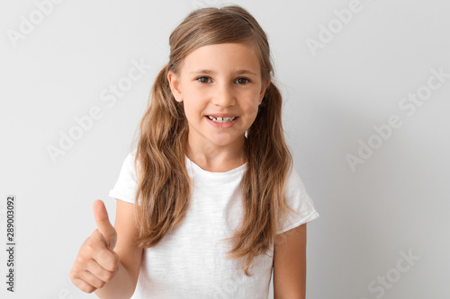 Wallpaper Mural Little girl in stylish t-shirt showing thumb-up on light background Torontodigital.ca