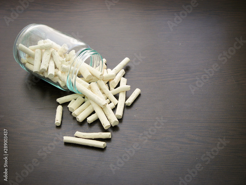 Kashk ( qurt, kurut, gurt or qurut) are poured from a glass jar on dark wooden surface.