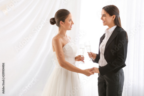 Beautiful lesbian couple with glasses of champagne during wedding ceremony