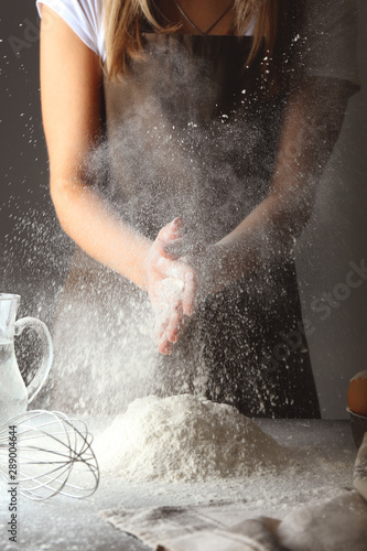 Woman clapping hands with flour in kitchen