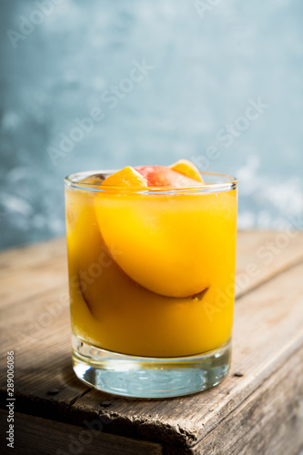 Fresh peach beverage in old fashioned glass on the rustic background. Selective focus.