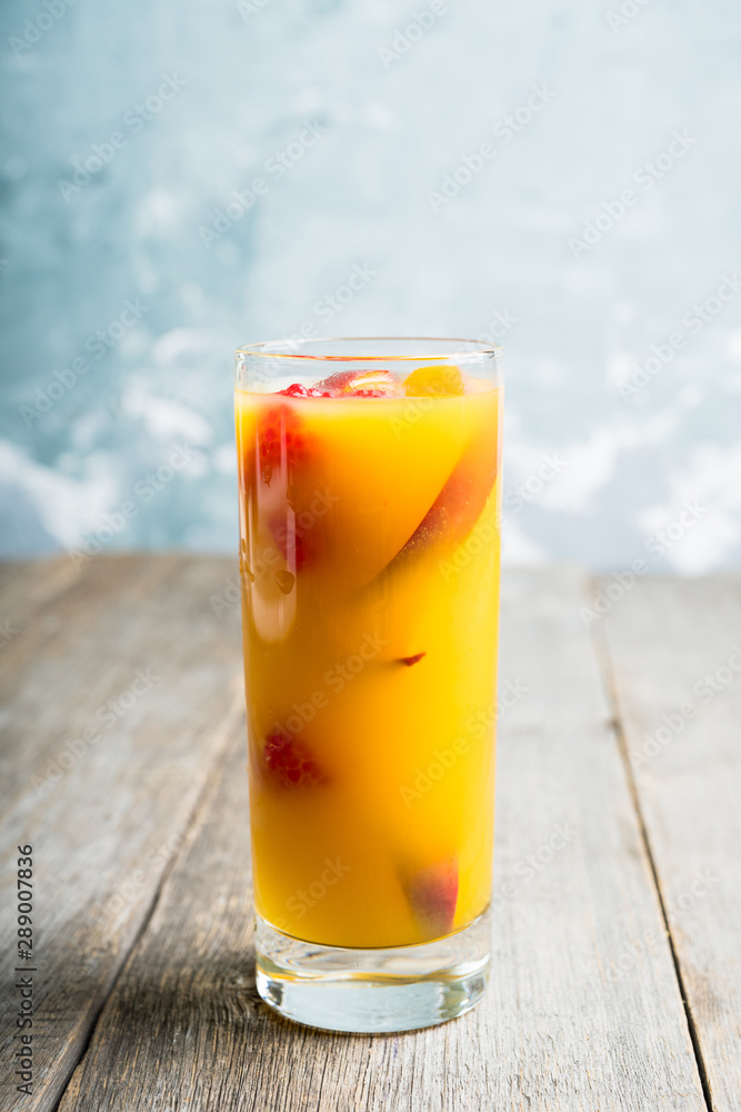 Fresh peach beverage with red ripe raspberry on the rustic background. Selective focus.