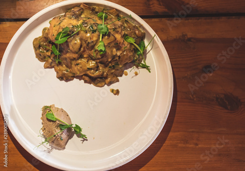 Wild mushrooms in creamy cheese sauce with fresh green oregano. Flat lay in wooden background.