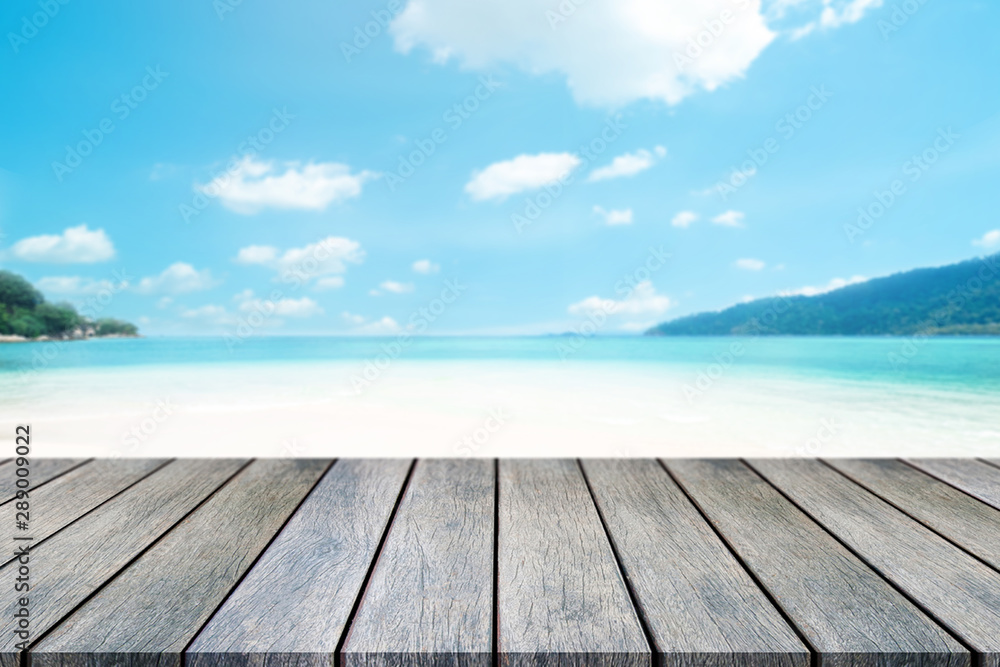 Perspective wooden table on top over blur sea in sunny day background. Beautiful sea and clouds in Thailand on summer, can be used mock up for montage products display or design layout. Perspective wooden table on top over blur sea in sunny day background. Beautiful sea and clouds in Thailand on summer, can be used mock up for montage products display or design layout.