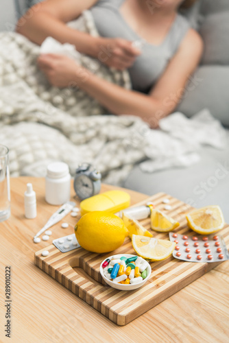 Young woman sick with colds and flu, self-medication at home with vitamins and pills