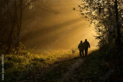 dwie osoby z psem na jesiennym spacerze © bogumilpason