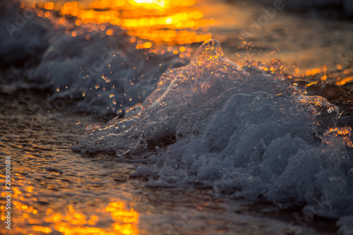 close up wave crashing on a beach at sunset