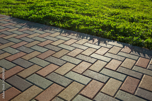 Colorful cobblestone road pavement and lawn divided by a concrete curb. Backlight. photo
