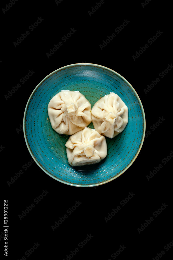 Fototapeta premium khinkali on a colored plate on a black background