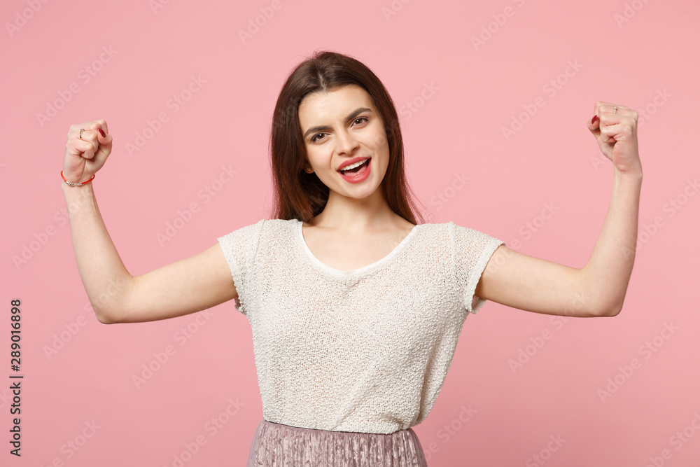 Strong young woman in casual light clothes posing isolated on pastel pink wall background, studio portrait. People sincere emotions lifestyle concept. Mock up copy space. Showing biceps, muscles. Strong young woman in casual light clothes posing isolated on pastel pink wall background, studio portrait. People sincere emotions lifestyle concept. Mock up copy space. Showing biceps, muscles.