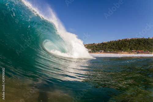 huge surfing wave crashing on the beach close up action photo taken while swimming