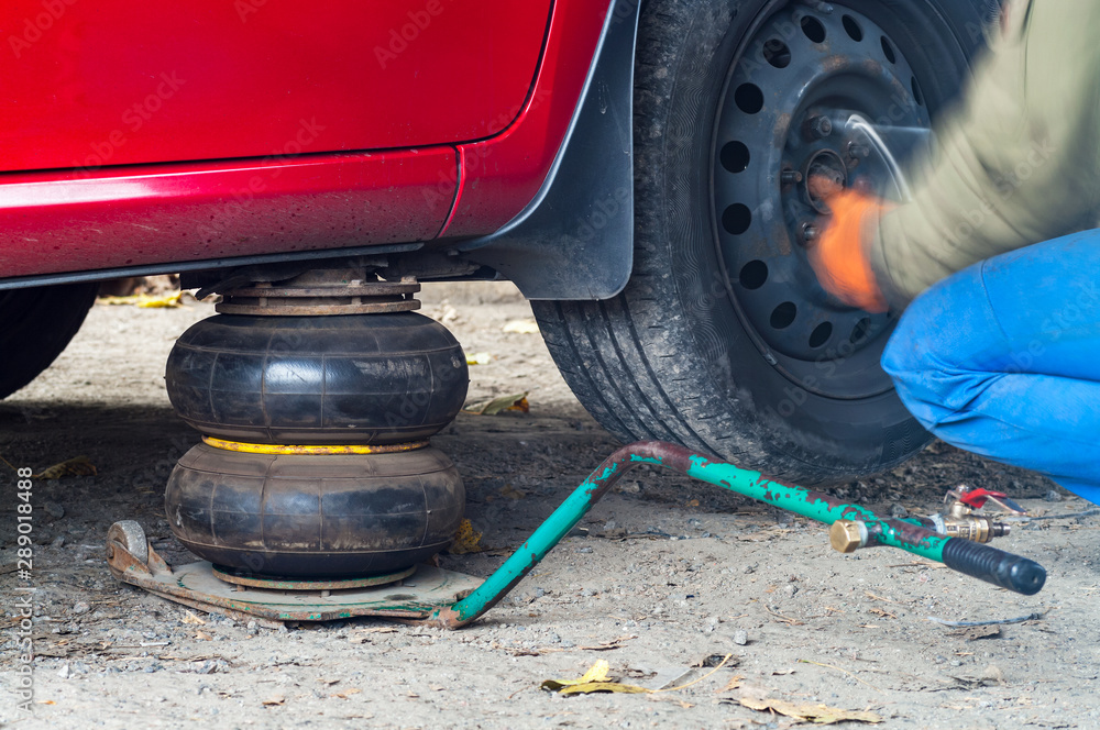 Repairman at works. Replacing wheels on a car, pneumatic jack holds the body. Repairman at works. Replacing wheels on a car, pneumatic jack holds the body.