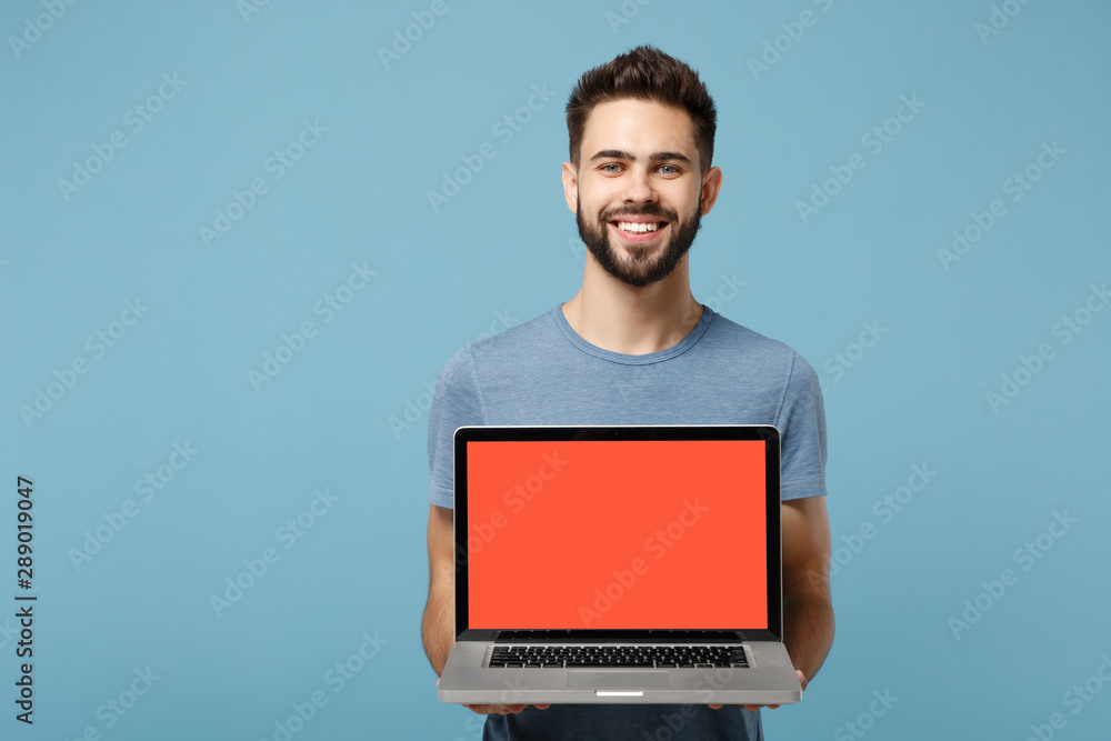 Young smiling handsome man in casual clothes posing isolated on blue wall background in studio. People lifestyle concept. Mock up copy space. Hold in hands laptop pc computer with blank empty screen. Young smiling handsome man in casual clothes posing isolated on blue wall background in studio. People lifestyle concept. Mock up copy space. Hold in hands laptop pc computer with blank empty screen.