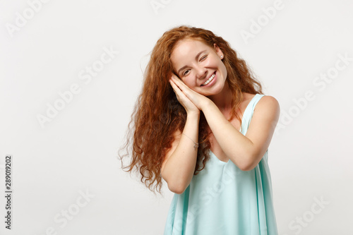 Young smiling redhead woman in casual light clothes posing isolated on white background in studio. People sincere emotions lifestyle concept. Mock up copy space. Sleep with folded hands under cheek.