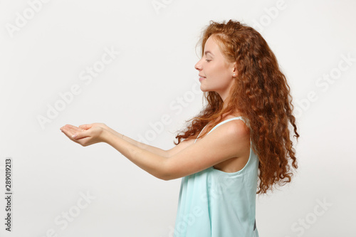 Side view of young redhead woman girl in casual light clothes posing isolated on white background studio portrait. People sincere emotions lifestyle concept. Mock up copy space. Holding something.