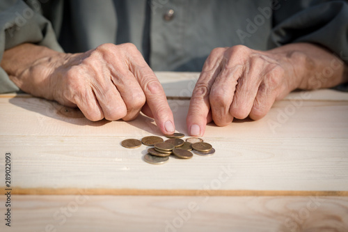 Hands of an elderly man holding coins. The concept of lack of money, the poor, the small pension of old people. Image.