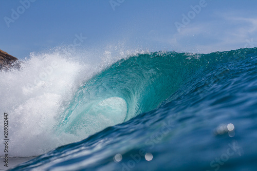 bright turquoise blue wave breaking on a coral reef off a tropical island
